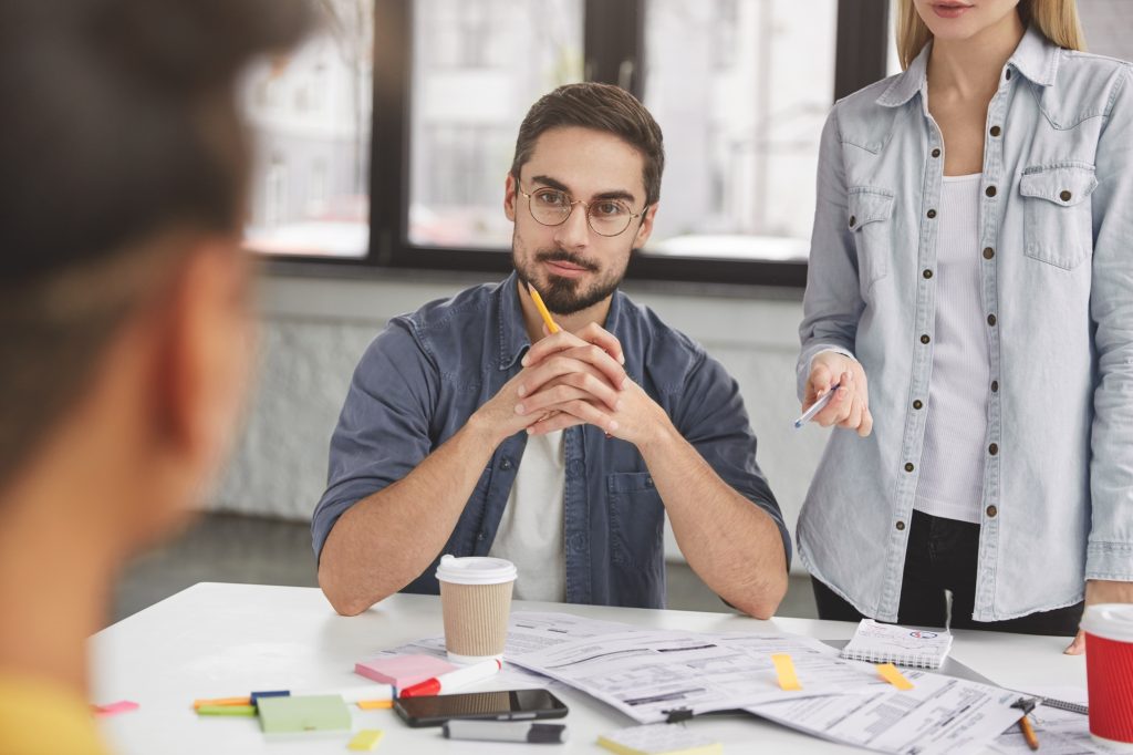 Three team members meet together to discuss idea of improvement financial situation, surrounded witn